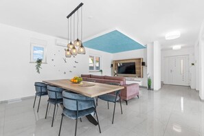 Een moderne keuken met een houten tafel, blauw plafond en een aan de muur bevestigde televisie.