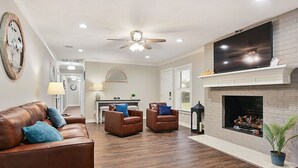 Een woonkamer met een open haard, leren banken en een flatscreen-televisie.