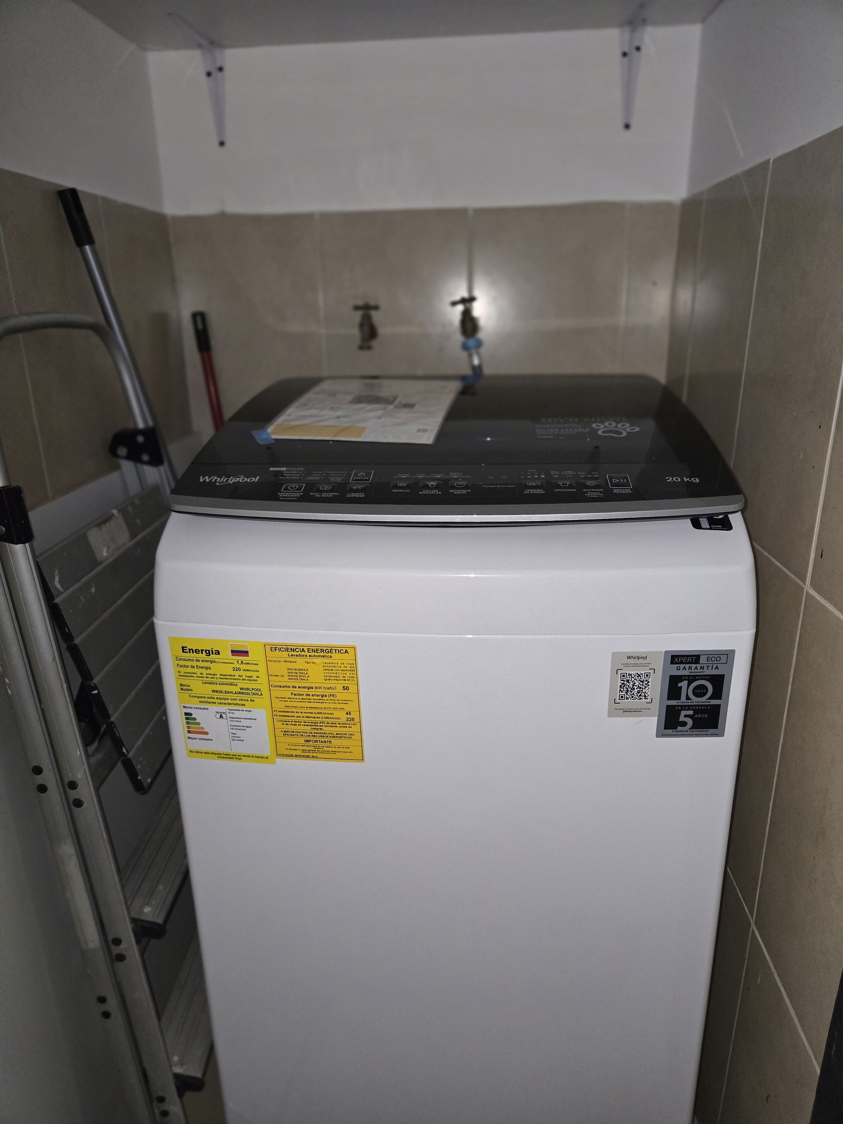 A compact washer-dryer unit with a control panel, a yellow energy efficiency label, and a QR code sticker.