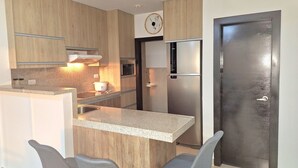A modern kitchen with wooden cabinets, a built-in microwave, a stainless steel refrigerator, and a granite countertop. - Lindo y moderno apartment in lovely Samborondon with WiFi, AC (Guayaquil)