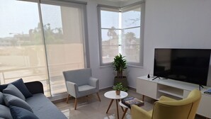 A modern living room with a sofa, armchairs, a TV, and a potted plant. - Lindo y moderno apartment in lovely Samborondon with WiFi, AC (Guayaquil)