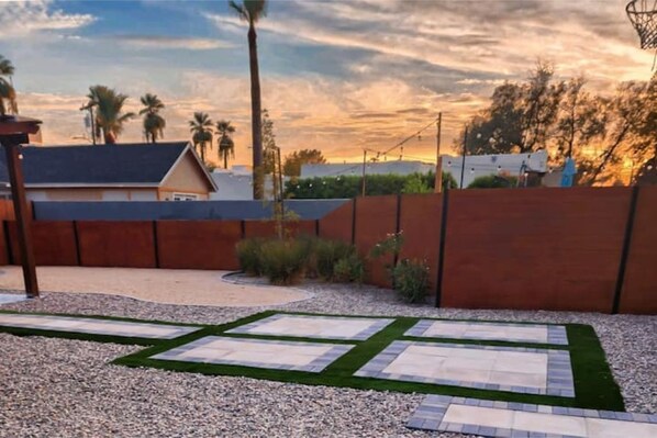 A landscaped garden with a pathway, palm trees, and a building in the background.