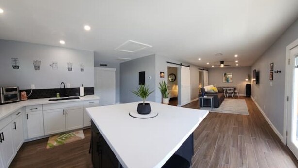 Una cocina moderna con armarios blancos, una isla central y una zona de comedor con mesa y sillas.