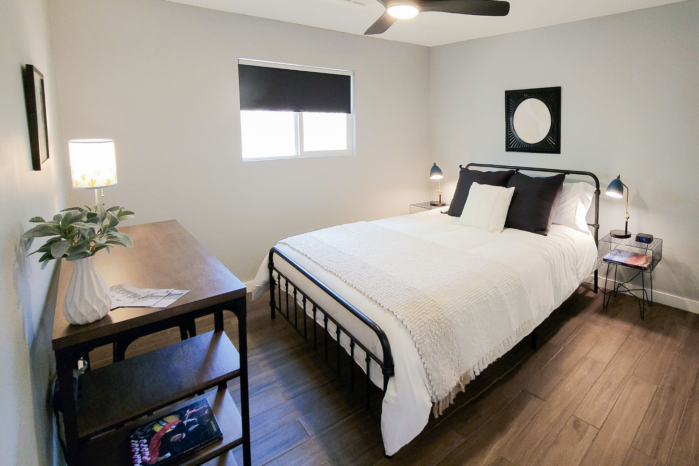 A bedroom with a bed, bedside tables, a desk, and a window.