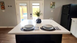 Una cocina moderna con una isla central, dos cubos de basura, una planta en maceta y una copa de vino.