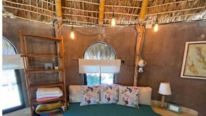 A cozy room with a bed, a shelf with folded towels, a lamp, and a framed picture on the wall. - Casita Vista: Ocean Views, Private Hot Tub & You! (Buenavista)