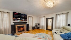 Un salon avec une cheminée, un canapé, une table basse et un téléviseur fixé au mur.