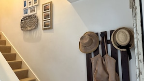 Una escalera con un muro blanco decorado con cuadros enmarcados y cestas tejidas.
