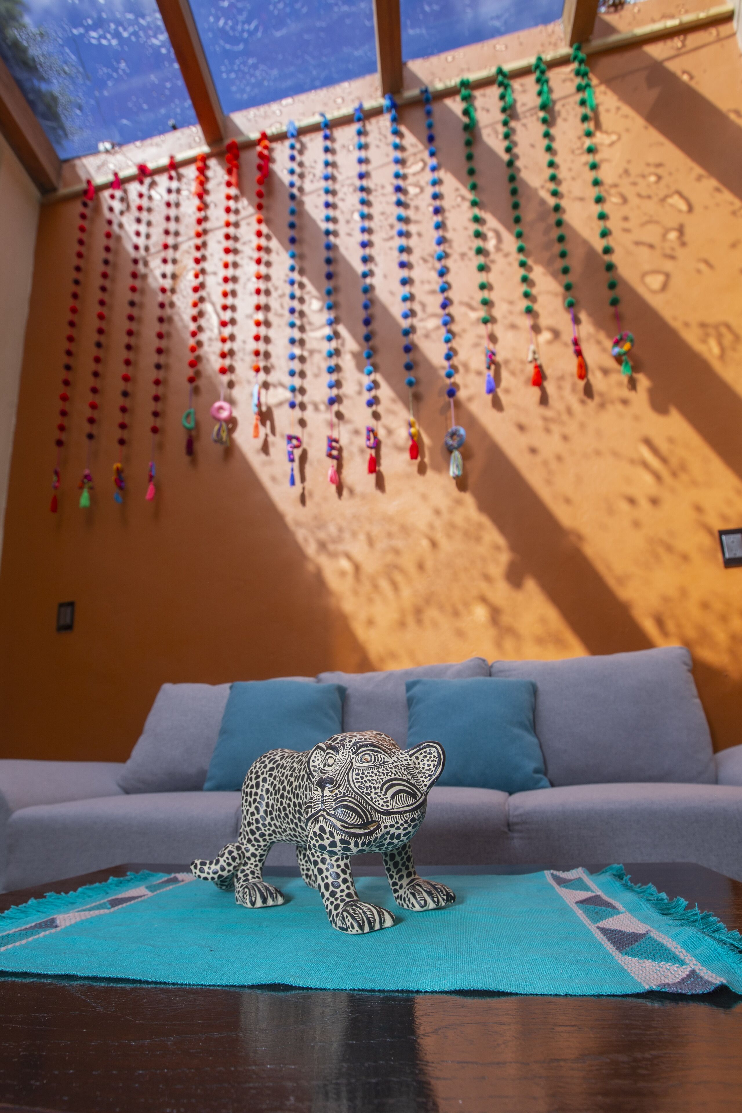 A room with a sofa, a decorative leopard figurine, and a wall adorned with colorful hanging ornaments.