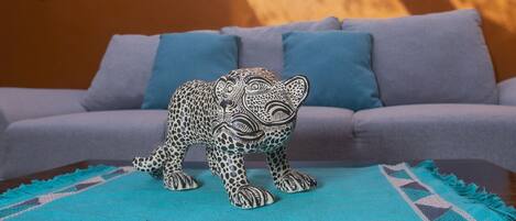 A room with a sofa, a decorative leopard figurine, and a wall adorned with colorful hanging ornaments.