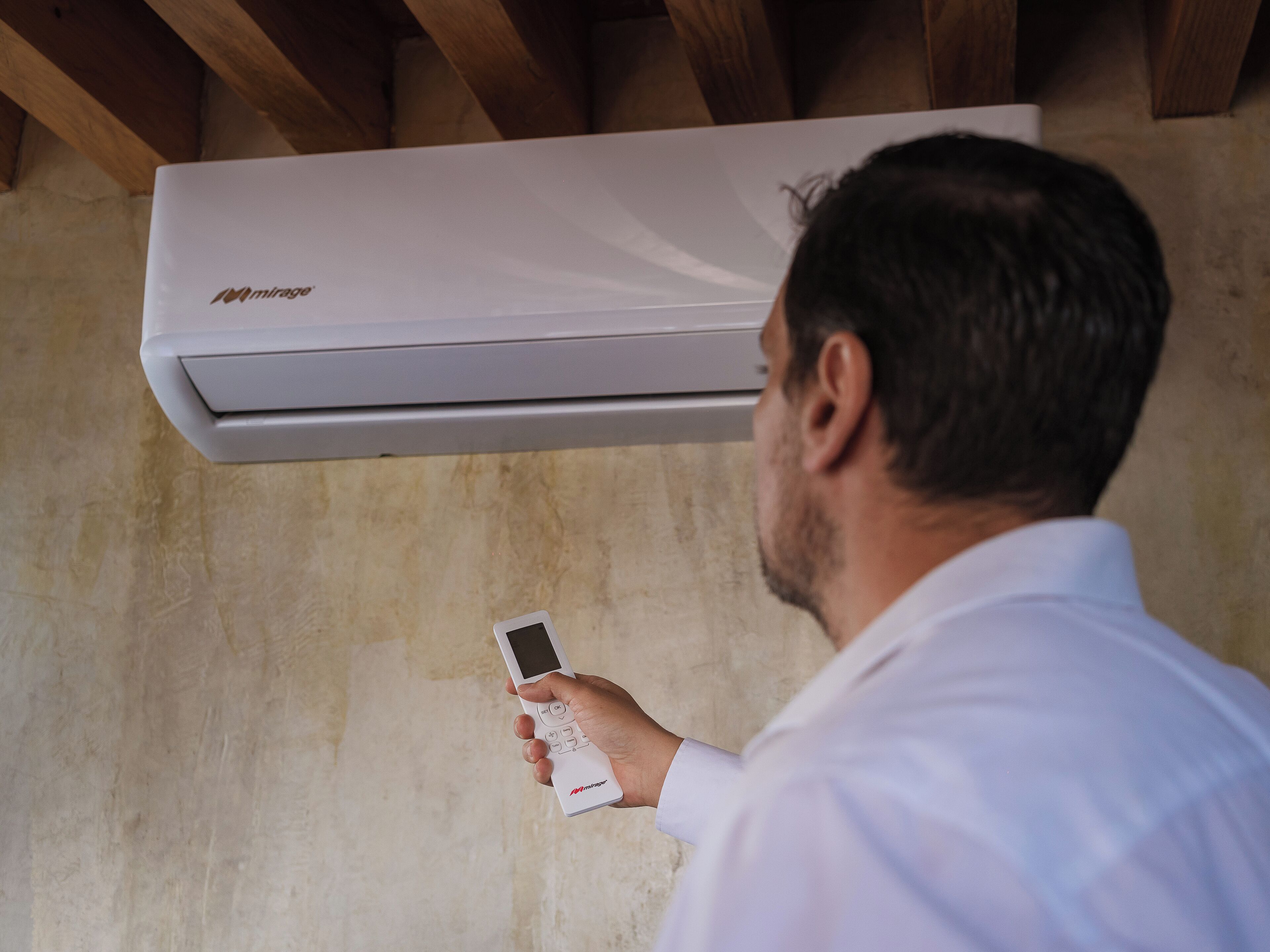 Iemand houdt een afstandsbediening voor een witte airconditioner.