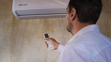 Iemand houdt een afstandsbediening voor een witte airconditioner.