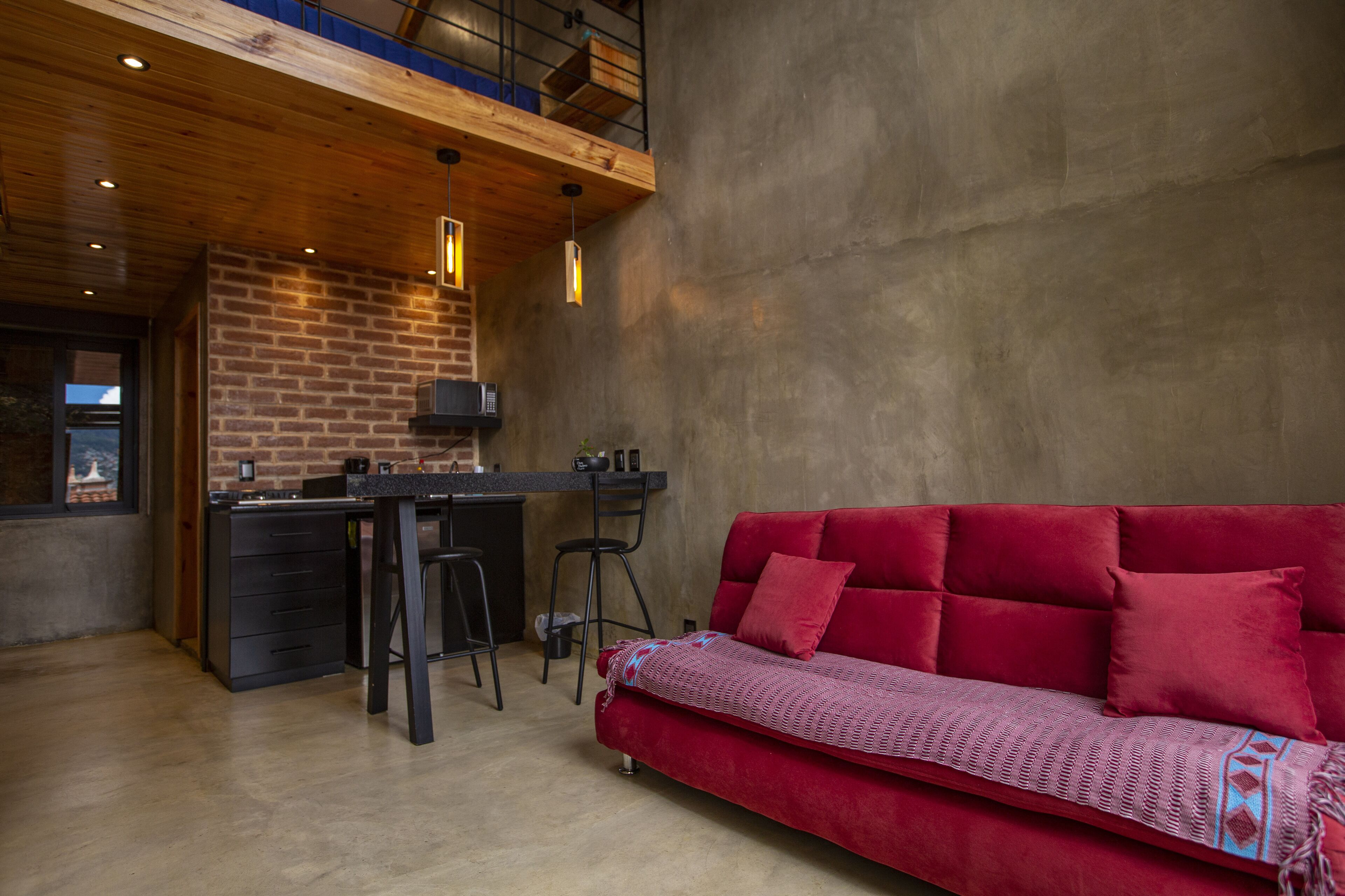 Une cuisine moderne avec un mur en briques, un plafond en bois et des tabourets de bar.