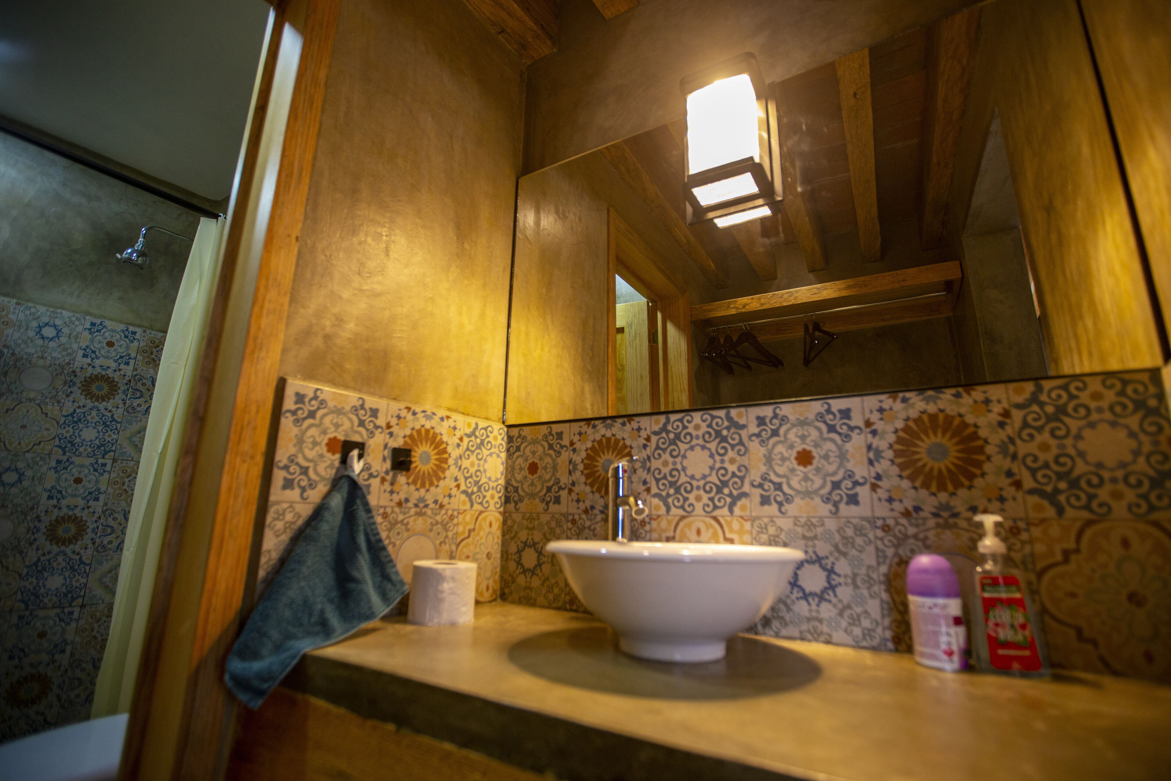 Une salle de bain avec un mur recouvert de carreaux derrière le lavabo, un lavabo, une serviette et un miroir.