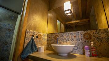 Une salle de bain avec un mur recouvert de carreaux derrière le lavabo, un lavabo, une serviette et un miroir.
