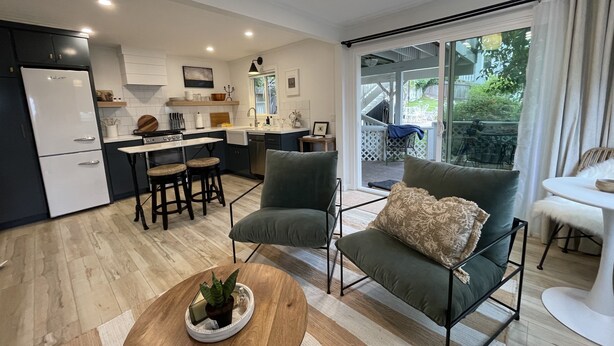 Une cuisine moderne équipée d’un réfrigérateur, d’une cuisinière et de tabourets de bar. On y trouve également un coin repas avec une table et des chaises, ainsi qu’un salon avec un canapé et une table basse.