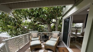 Un balcon avec des fauteuils en osier, un sol à carreaux et un paillasson.
