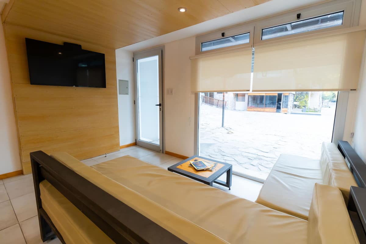 Una habitación moderna con sofá, una mesita y un televisor montado en la pared.