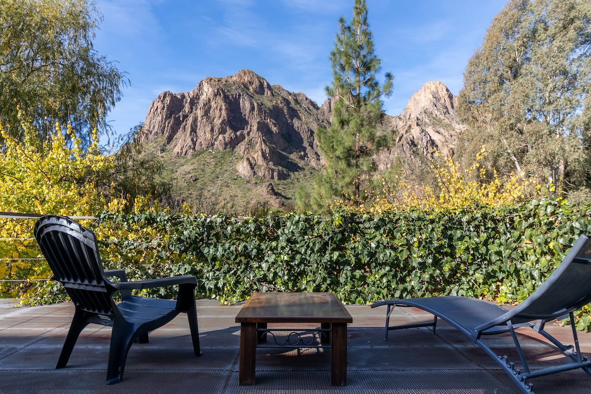 Un patio con dos sillas y una mesa, con vistas a un paisaje montañoso.