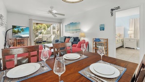 A dining area with a wooden table set for four, a ceiling fan, and a view of the outdoors. - Beach Castle Resort, Pool, Private Beach! (Longboat Key)