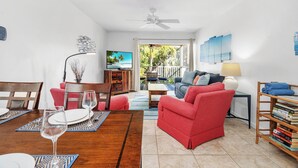 A living room with a dining area, a red sofa, a television, and a bookshelf. - Beach Castle Resort, Pool, Private Beach! (Longboat Key)
