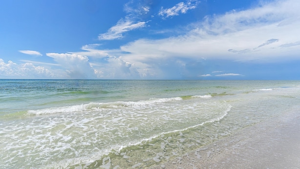 A beach with clear water, gentle waves, and a wide sandy shore under a blue sky with scattered clouds. - Beach Castle Resort, Pool, Private Beach! (Longboat Key)