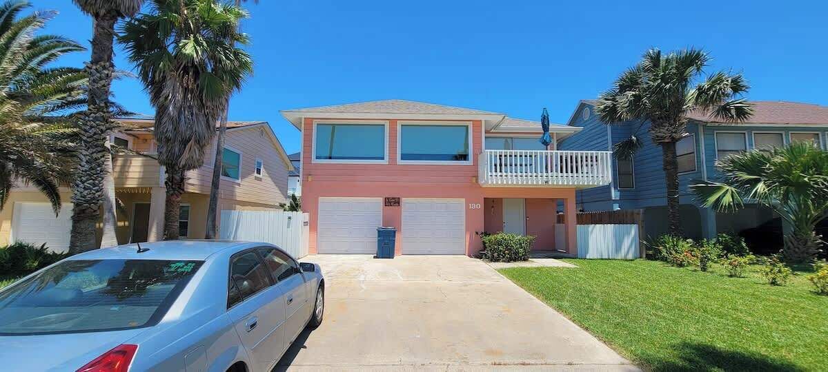 A two-story house with a garage, a balcony, and a well-maintained lawn.