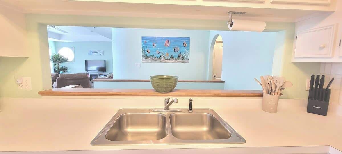 A kitchen with a double sink, a green bowl on the counter, and a knife block to the right.