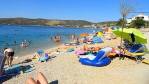 A beach with sun loungers, umbrellas, and people swimming. - Apartment in Ražanj with Seaview, Terrace, Air condition, WIFI (4773-3) (Ražanj)