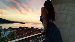 A person standing on a balcony overlooking a body of water with a sunset in the background. - Apartment in Ražanj with Terrace, Air condition, WIFI, Washing machine (4773-4) (Ražanj)