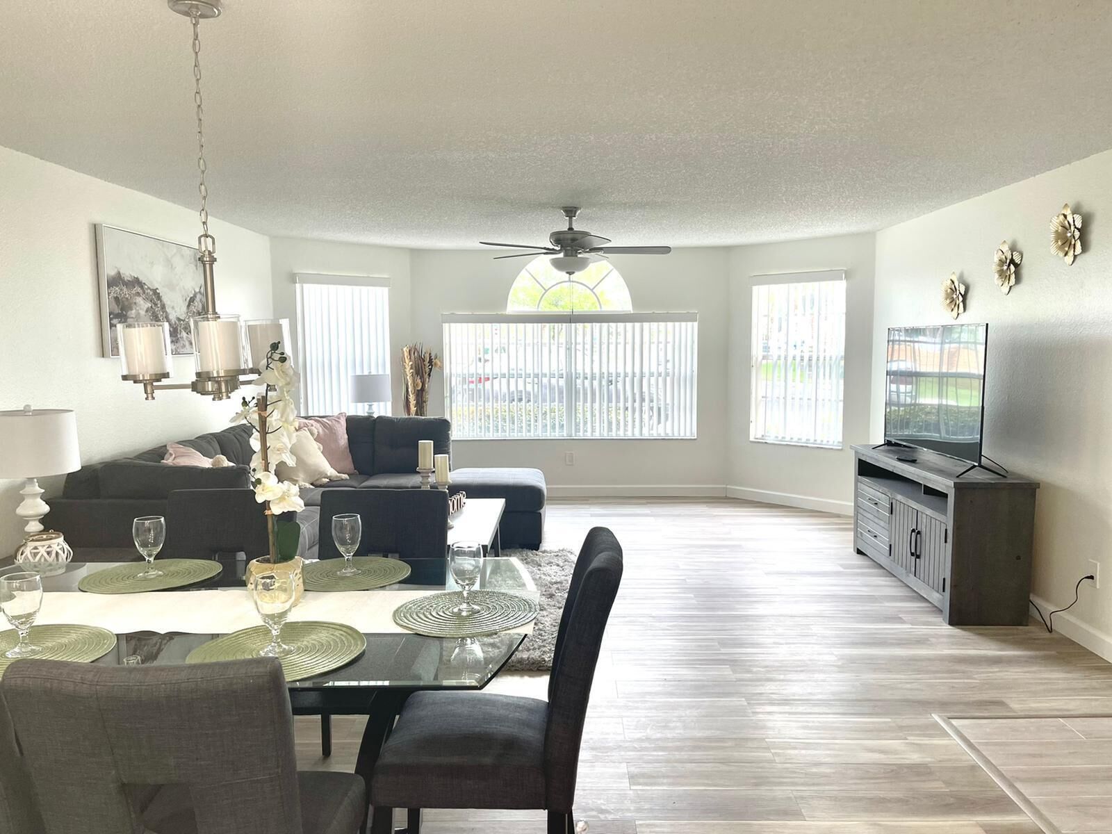 A spacious living room with a dining area, a ceiling fan, and a television on a cabinet.
