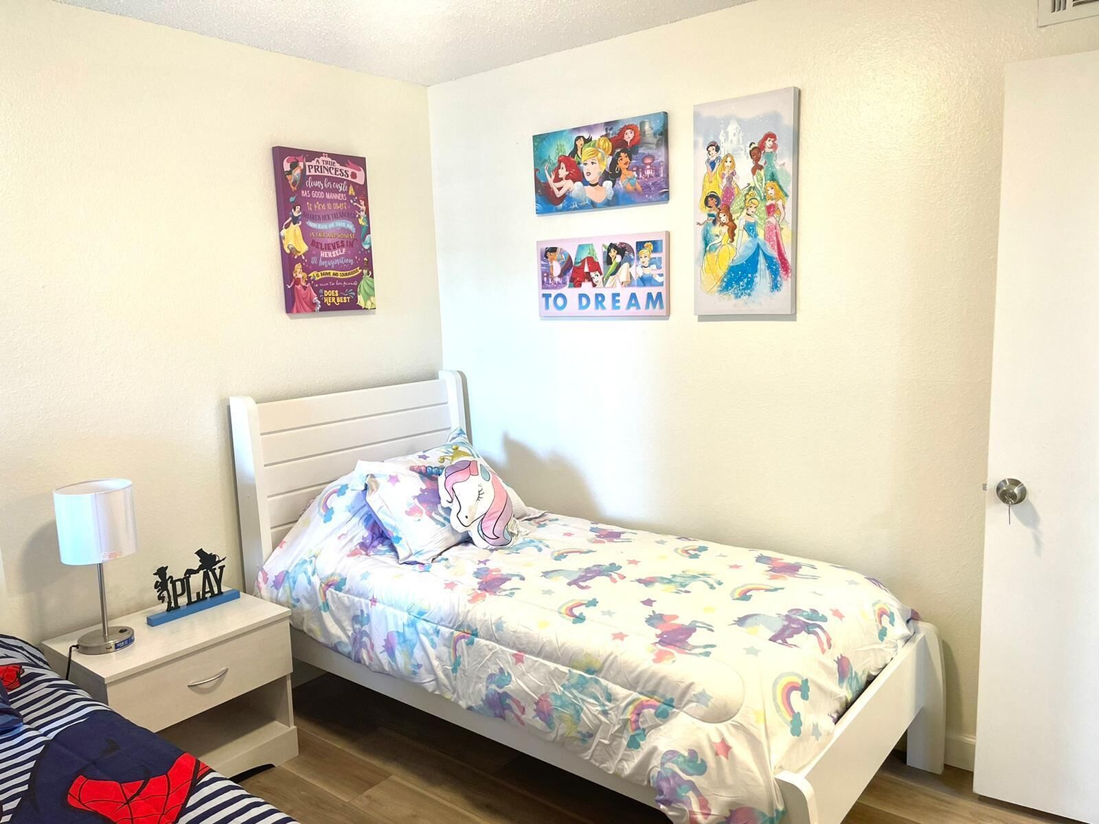A bedroom with a bed, nightstand, and wall art.
