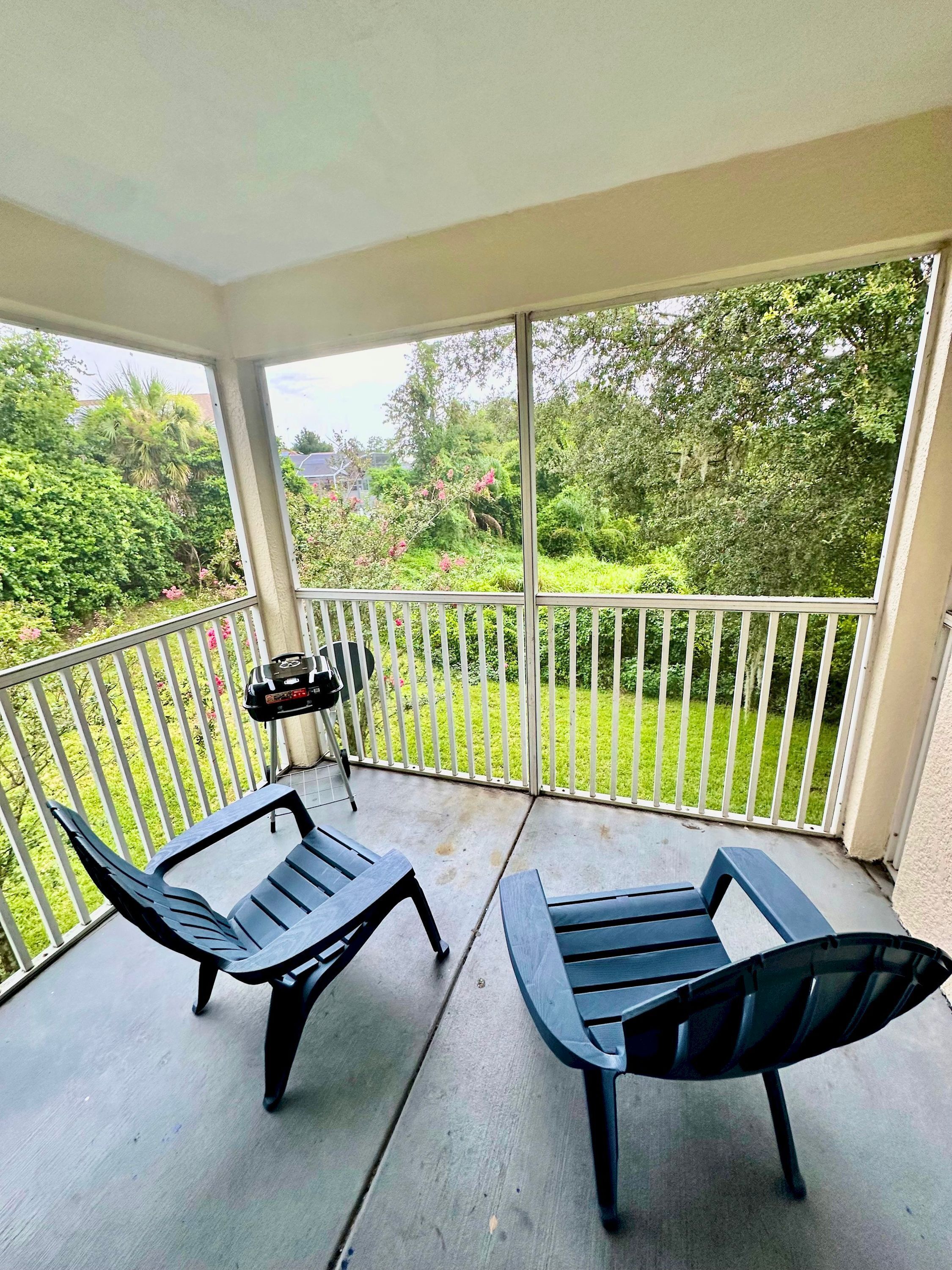 Een balkon met twee stoelen en een tafel, met uitzicht op een weelderige tuin.