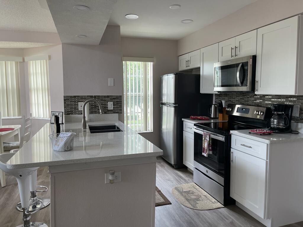 A modern kitchen with white cabinetry, stainless steel appliances, and a central island.