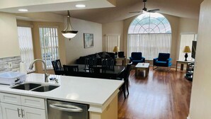 A spacious kitchen with a large island, a dining area with a table and chairs, and a living room with a sofa and a coffee table. - Grand Premier 3BD Condo Apartment Near Disney Parks 6 (Kissimmee)