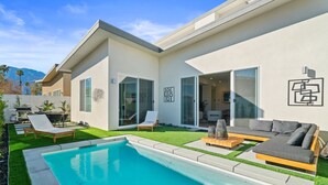 A modern house with a swimming pool, a patio with outdoor furniture, and a large sliding glass door. - Brand new luxury home near Tahquitz Creek Golf Course with mountain views! (Palm Springs)