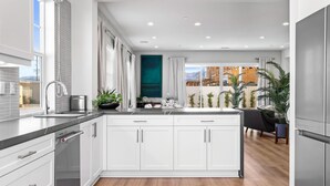 A modern kitchen with white cabinets, a central island, and a large window. - Brand new luxury home near Tahquitz Creek Golf Course with mountain views! (Palm Springs)