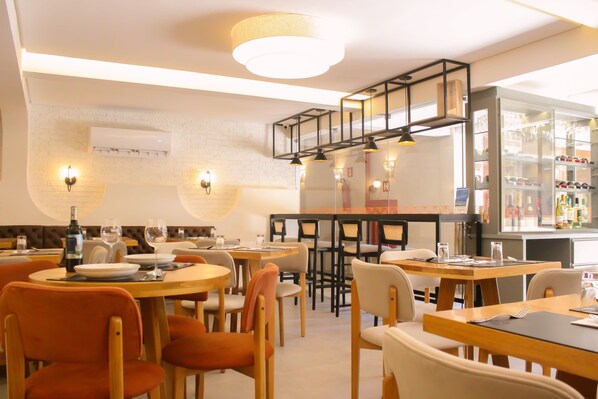 A restaurant with round tables, chairs, and a bar area. - Pousada Vila de Pedra (Jijoca de Jericoacoara)