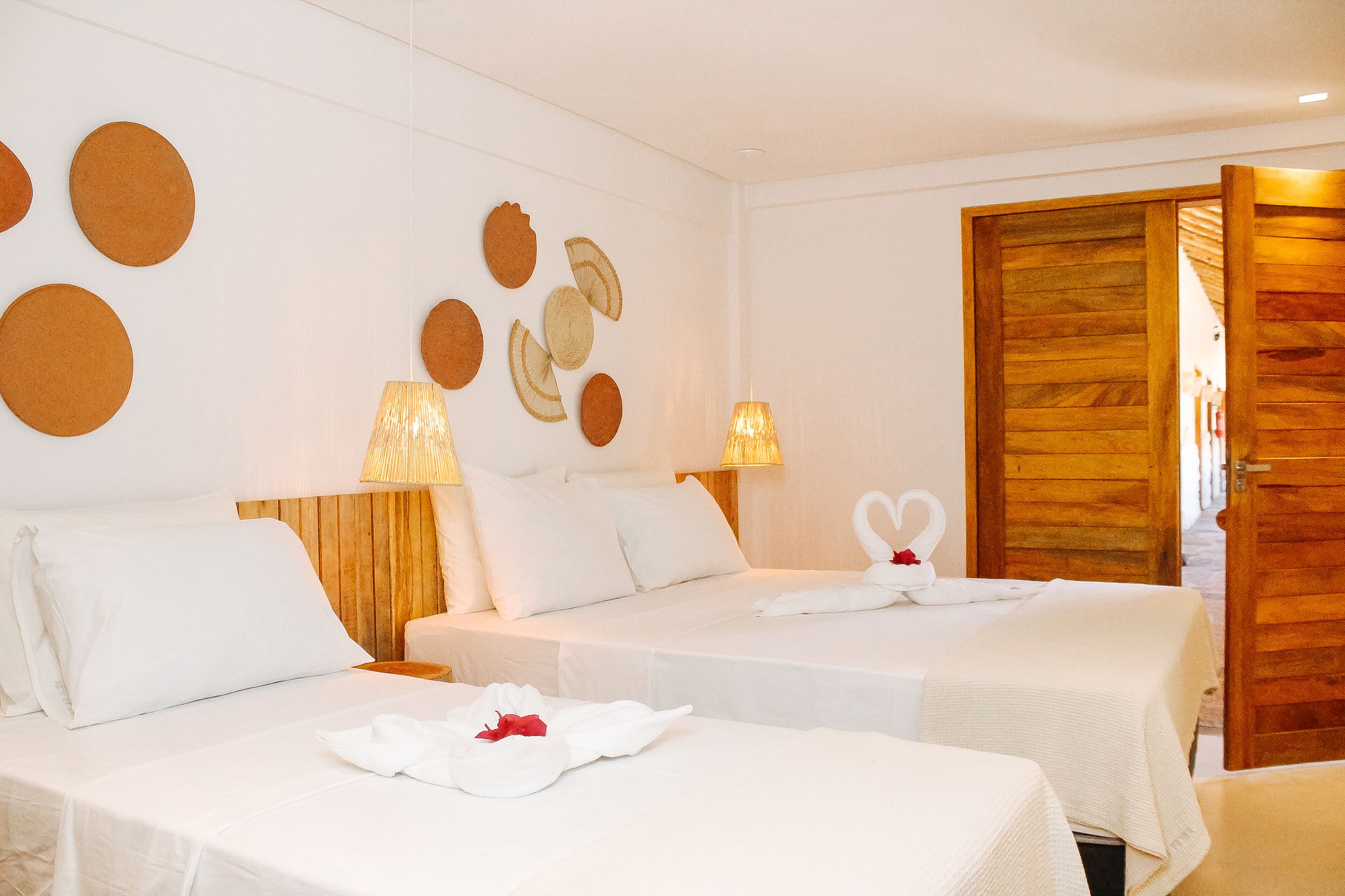 Una habitación de hotel con dos camas, una puerta de madera y decoración en la pared.