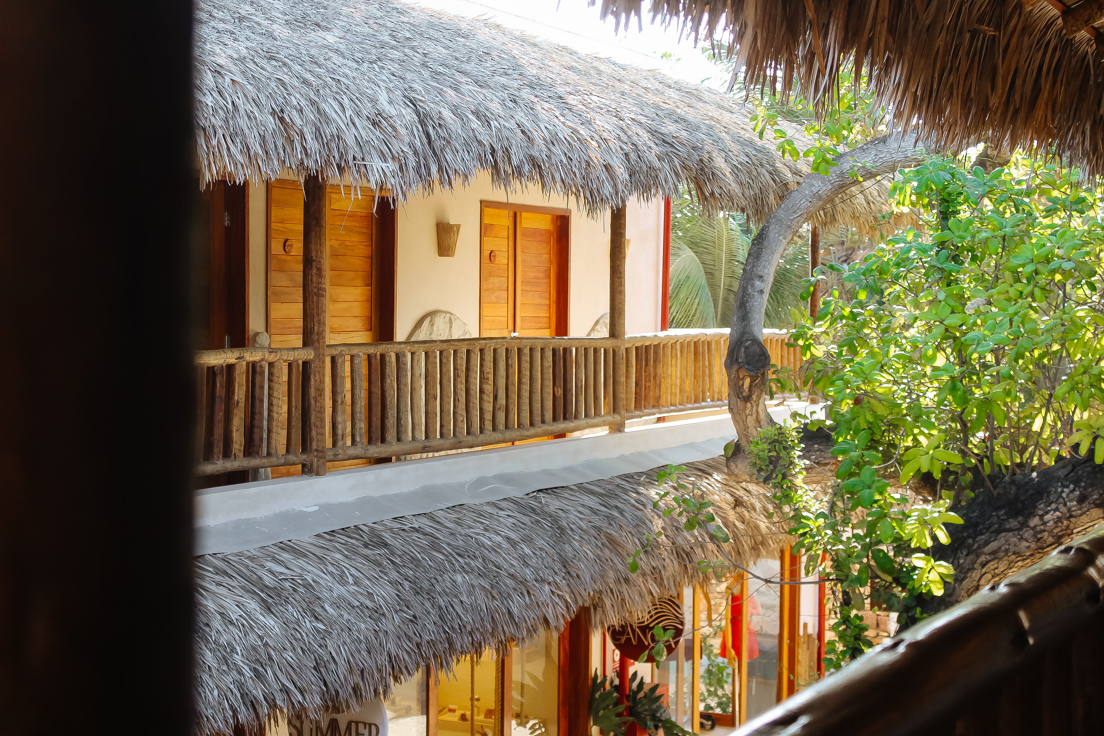 A thatched-roof building with wooden balconies and a stone wall.