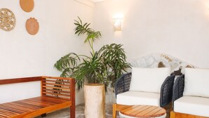 Ein gemütlicher Sitzbereich mit einer Holzbank, einem runden Holztisch, einem weißen Sofa und einem Blumentopf.