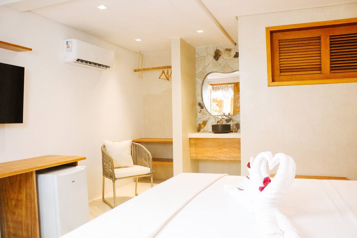 Une chambre d’hôtel équipée d’un lit, d’un bureau, d’une chaise, d’un miroir et d’un appareil de climatisation.