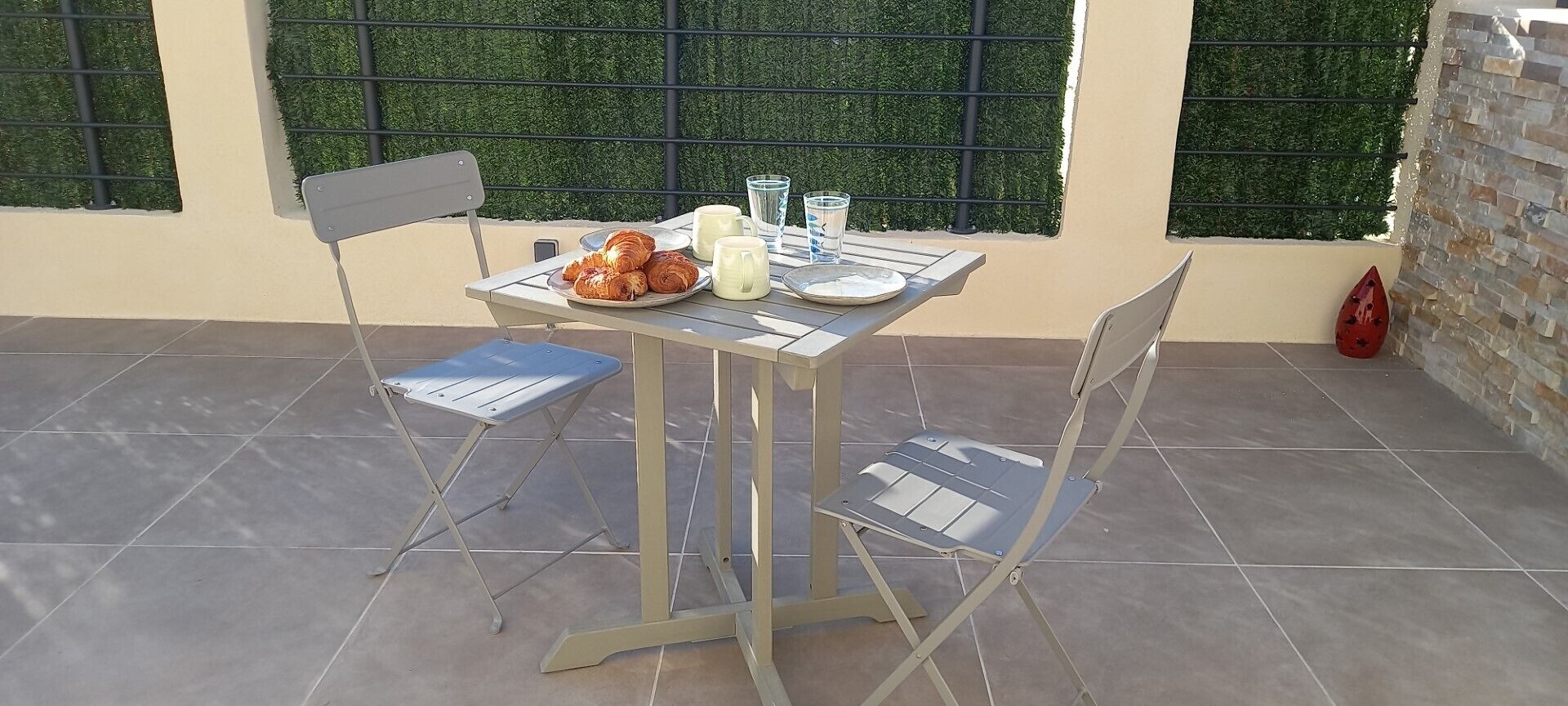 A patio table with chairs, a plate of pastries, and glasses.