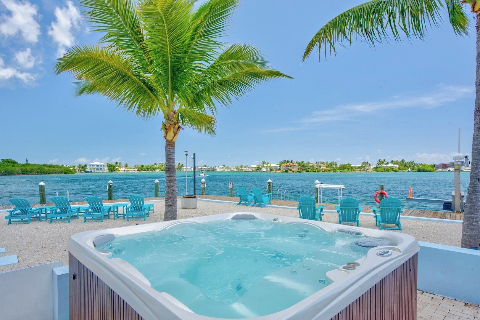 A hot tub area with a pool, chairs, and a view of the water and buildings.