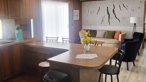 Een ruime keuken met houten kastjes, een centraal eiland en een eethoek met stoelen.