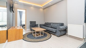 Una sala de estar moderna con un sofá gris, una mesa de centro de madera, un sillón gris y una pequeña mesita auxiliar de madera.