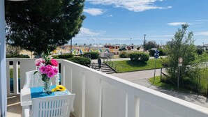 A balcony with a white railing, a table with a blue tablecloth, and a vase with flowers. - Cozy Apartment Facing the sea (San Michele al Tagliamento)
