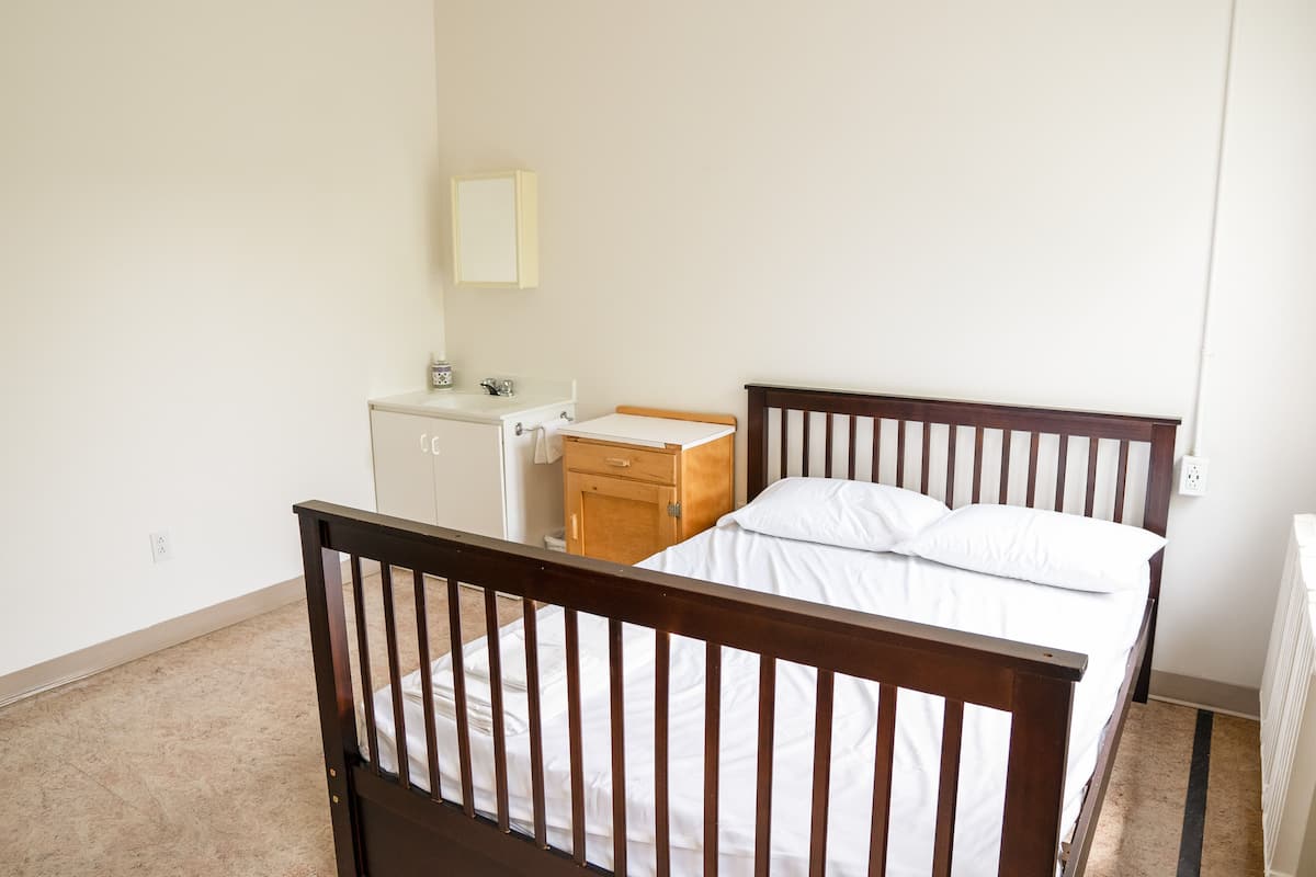 Un dormitorio con una cama de madera, una mesita de noche, un aparador y un espejo en la pared.