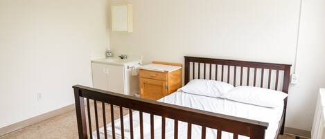 A bedroom with a wooden bed, a nightstand, a dresser, and a mirror on the wall.