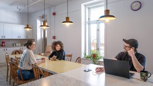 Moderni keittiö, jossa on valkoiset kaapit, riippuvalaisimet ja suuri ikkuna.